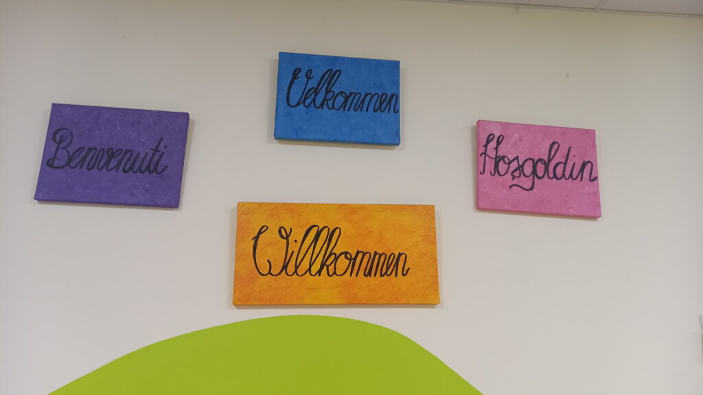 Vier farbige Wiederholungen der Willkommen-Begriffe in verschiedenen Sprachen.