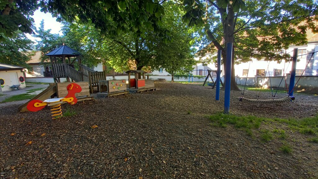Kinderspielplatz mit Gras, Spielanlage, Holzspielzeug und Fahne.