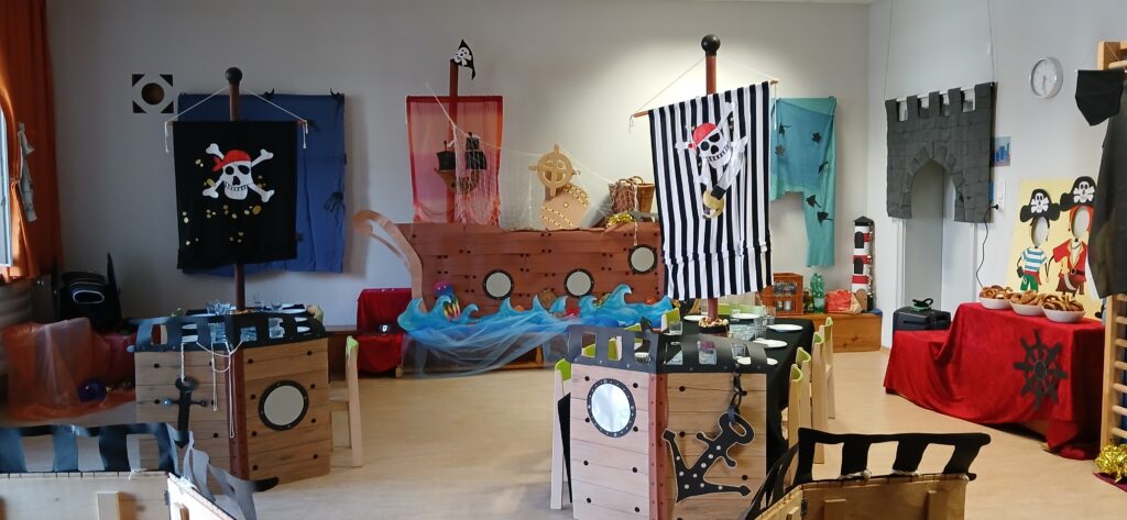 Piratenschiff in Klassenzimmer, festlich dekoriert mit Flaggen und Schiffsdekor.