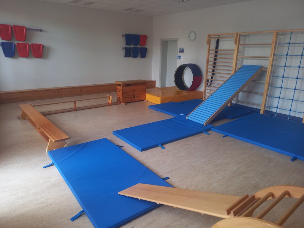 Gymnastikraum mit Matten, Rutsche, Laufbahn und Trainingsgeräten.