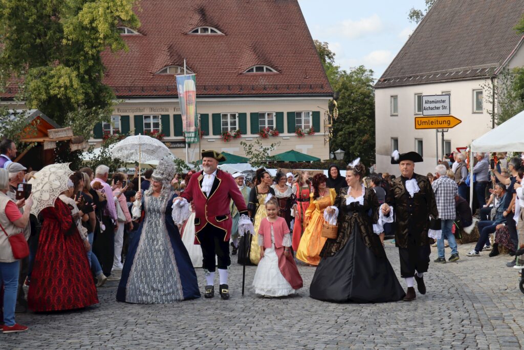 Markt Altomünster: Traditioneller Markt mit historischem Ambiente, Menschen in historischen Kostümen und farbenfrohem Marktplatz.