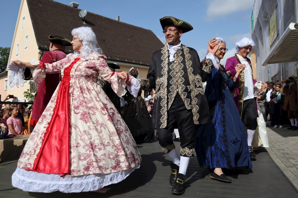 Dance mit Personen in historischen Kostümen auf einer Straße.