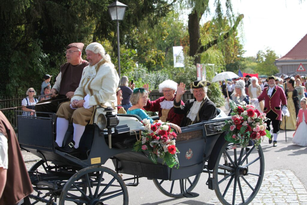 Kutsche mit Menschen in historischen Kostümen auf einer Parade in Altomünster.
