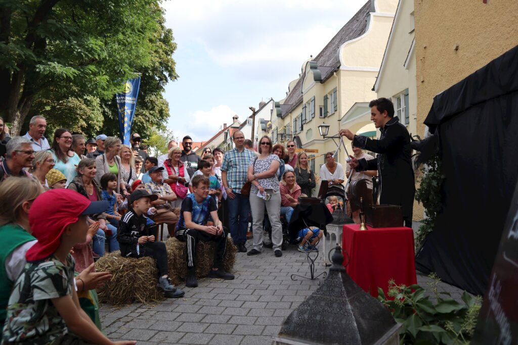 Markt Altomünster: Menschen am Markt mit Besucher und Leinwand im Hintergrund.