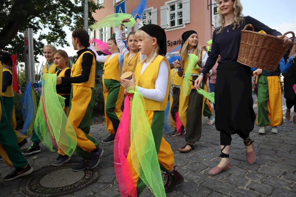 Jugendliche mit leuchtenden Kostümen und Körbchen bei Marktplatz.