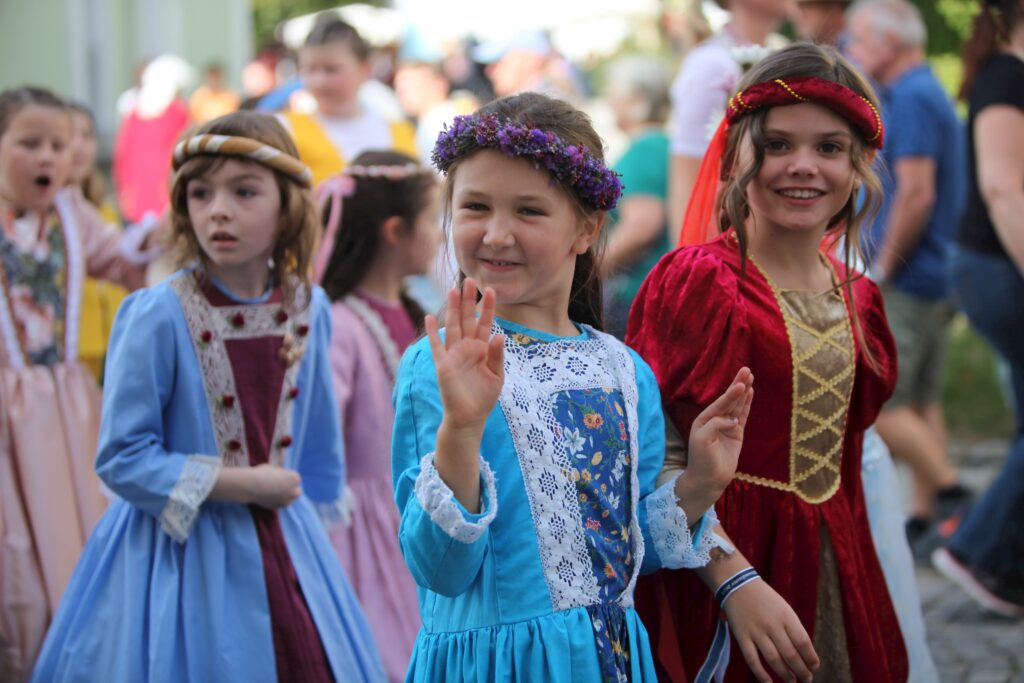 Zwei Kinder in farbenfrohen Kleidern bei einem Markt in Altomünster.