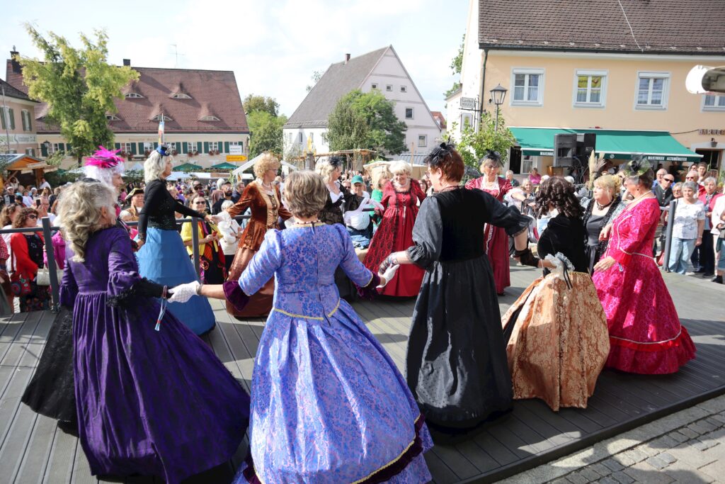 Dichter mit Damen in historischen Kostümen tanzen auf der Marktschaan.