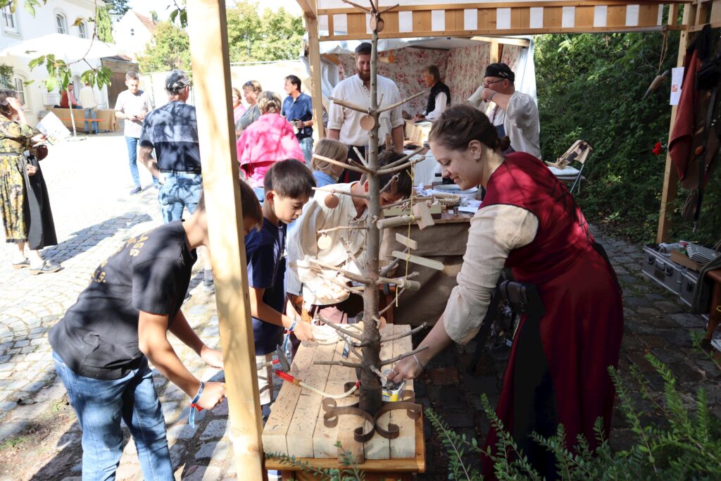 Markt Altomünster: Menschen beim Basteln auf einem Holzgestell.