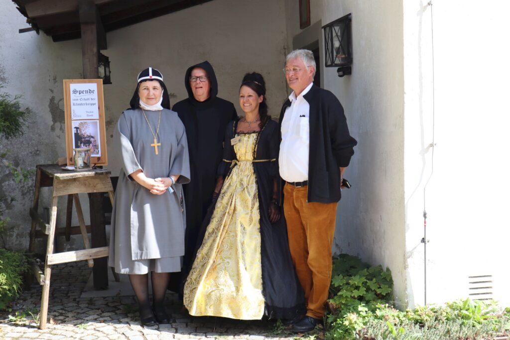 Vier Personen im historischen Stil vor einer Wand