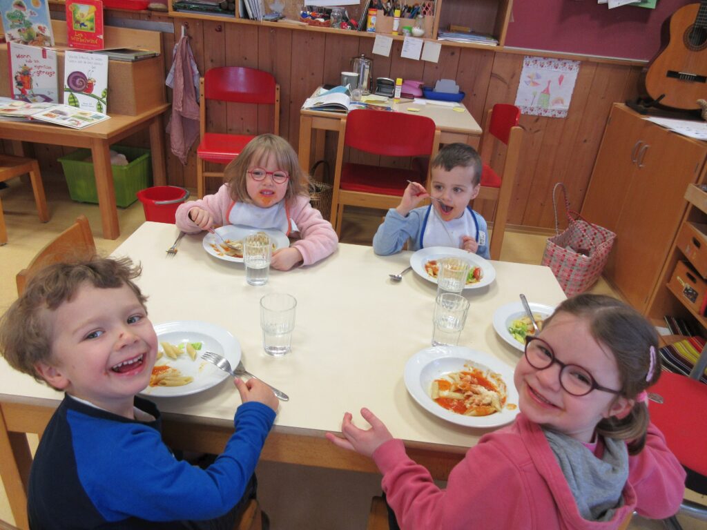 Vier Kinder beim gemeinsamen Essen in einer Schule.