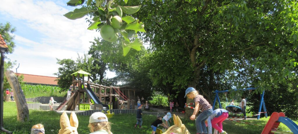 Schüler spielen im Spielplatz mit Bäumen und Obst auf dem Spielplatz in Altomünster.