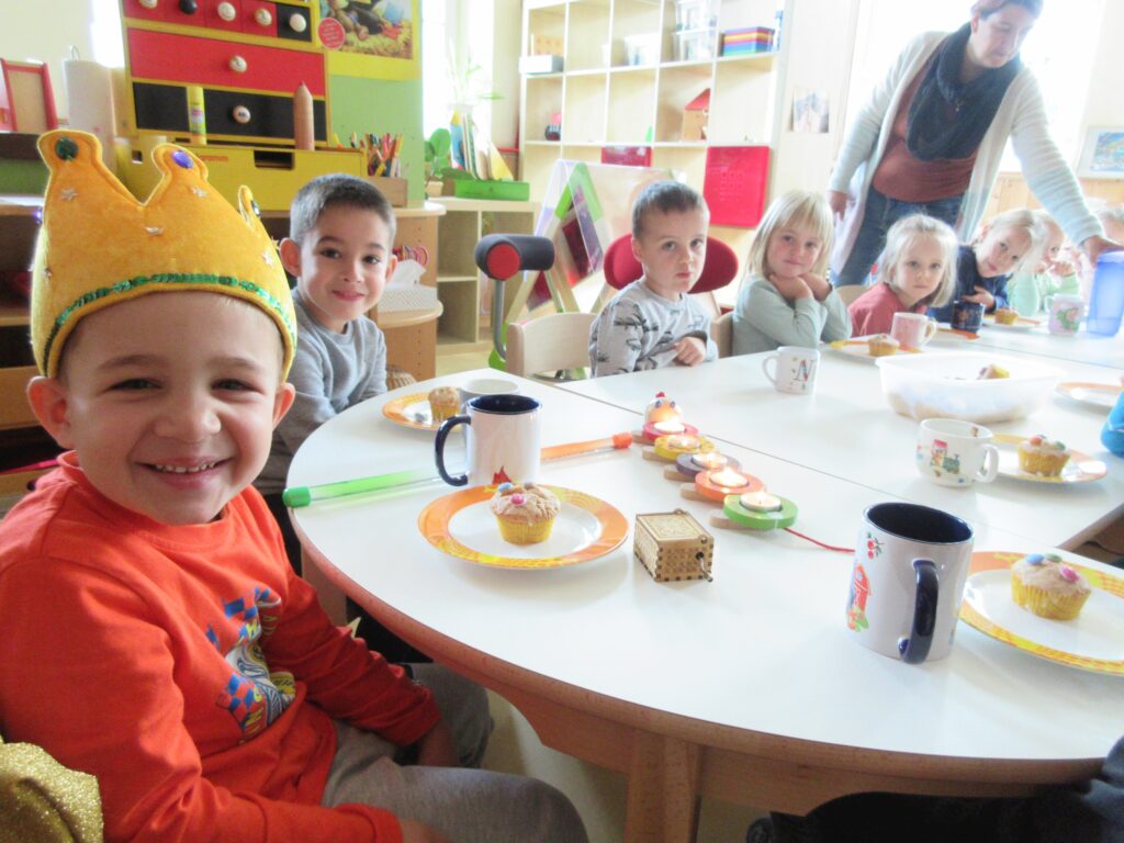 Ein Kind mit Krone und Muffins in einer Kita.
