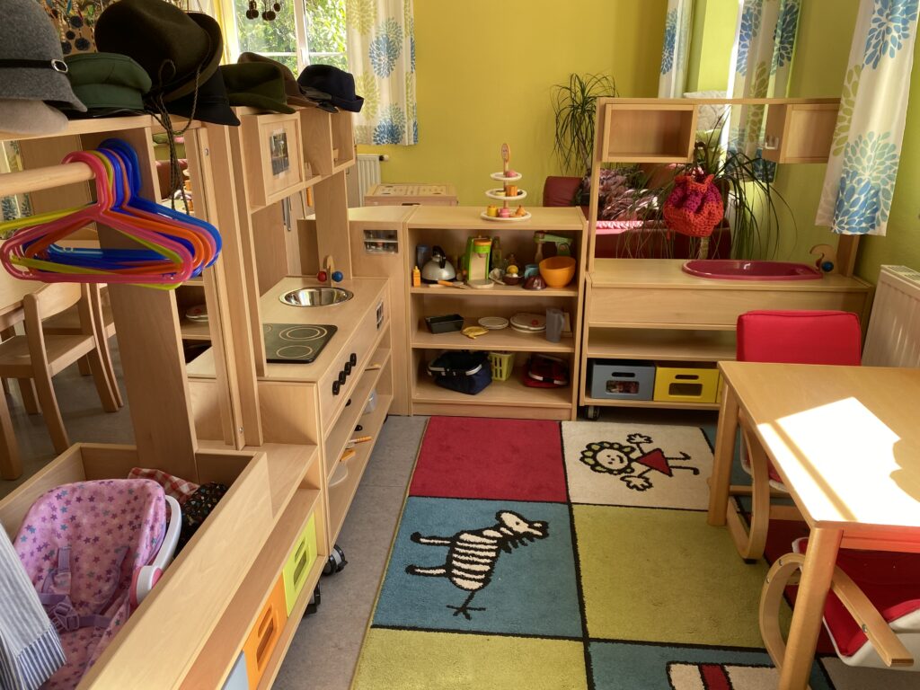 Ein Spielzimmer mit Kinderschrank, Spielküche, Klassenzimmer und Kindersitz.