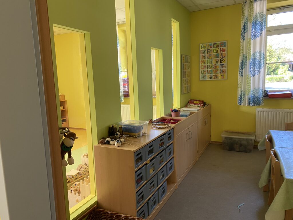 Gemeinschaftsraum mit Kinderspielzeug und Alphabetkarte.