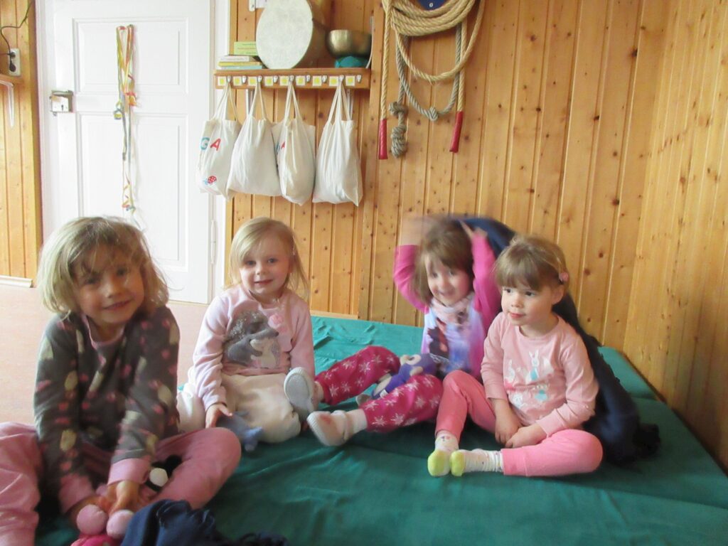 Vier Kinder auf einer Matte in einer kinderfreundlichen Umgebung.