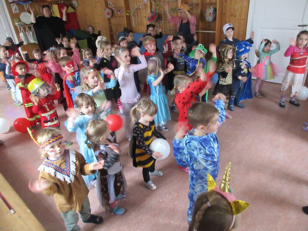 Gruppe von Kinder in Kostümen tanzen in einem Spielzimmer.