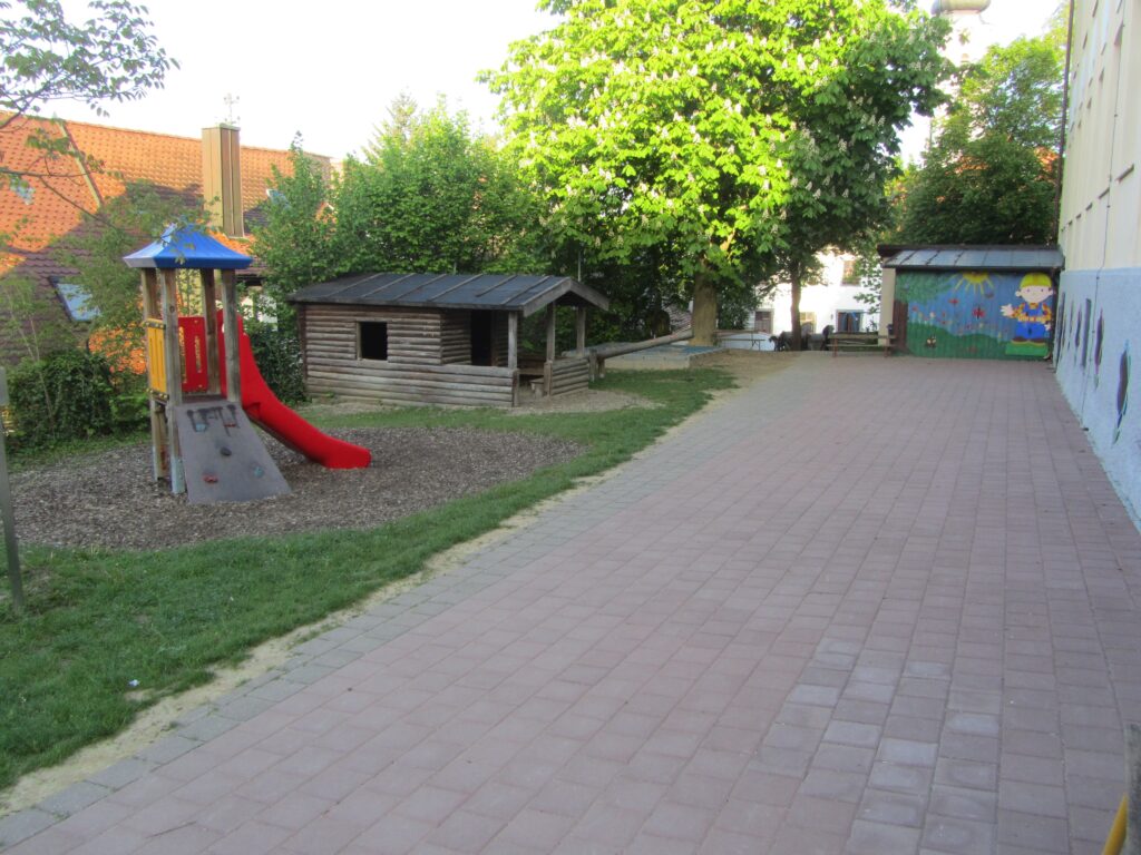 Pfad im Spielplatz mit Klettergerüst und Holzhaus im Grünen.