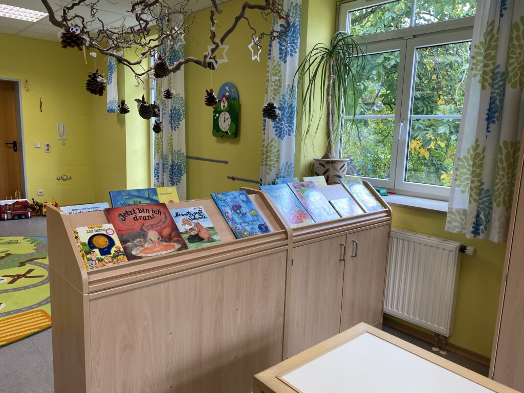 Kinderzimmer mit Bücherregal, Pflanze und Spielzeug.