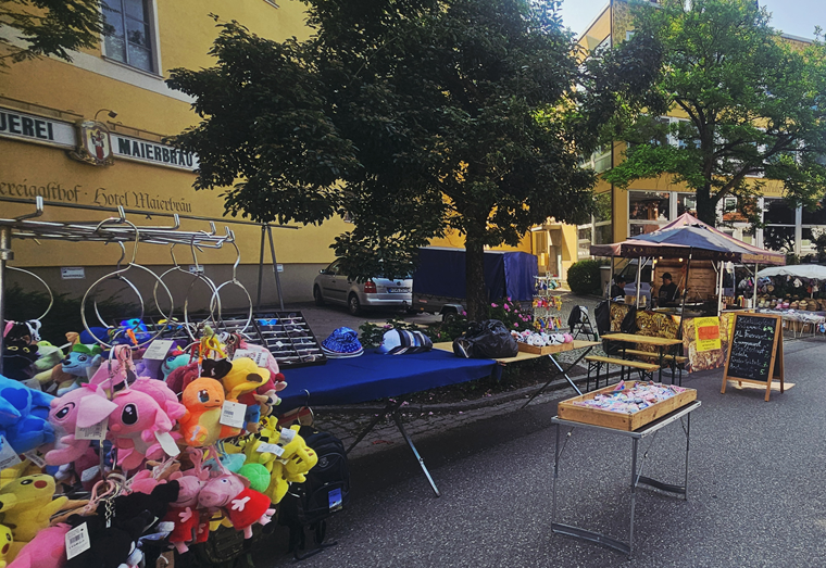 Leider haben wir keinen Titel zu diesem Bild. Wir arbeiten daran und bitten um Ihr Verständnis. Markt in Altomünster mit Plüschspielzeug und Ständen am Eingang zum Hotel.