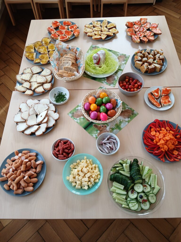 Tisch mit buntem Obst- und Gemüsebuffet, Fisch, Käse, Salat und gekochten Speisen.