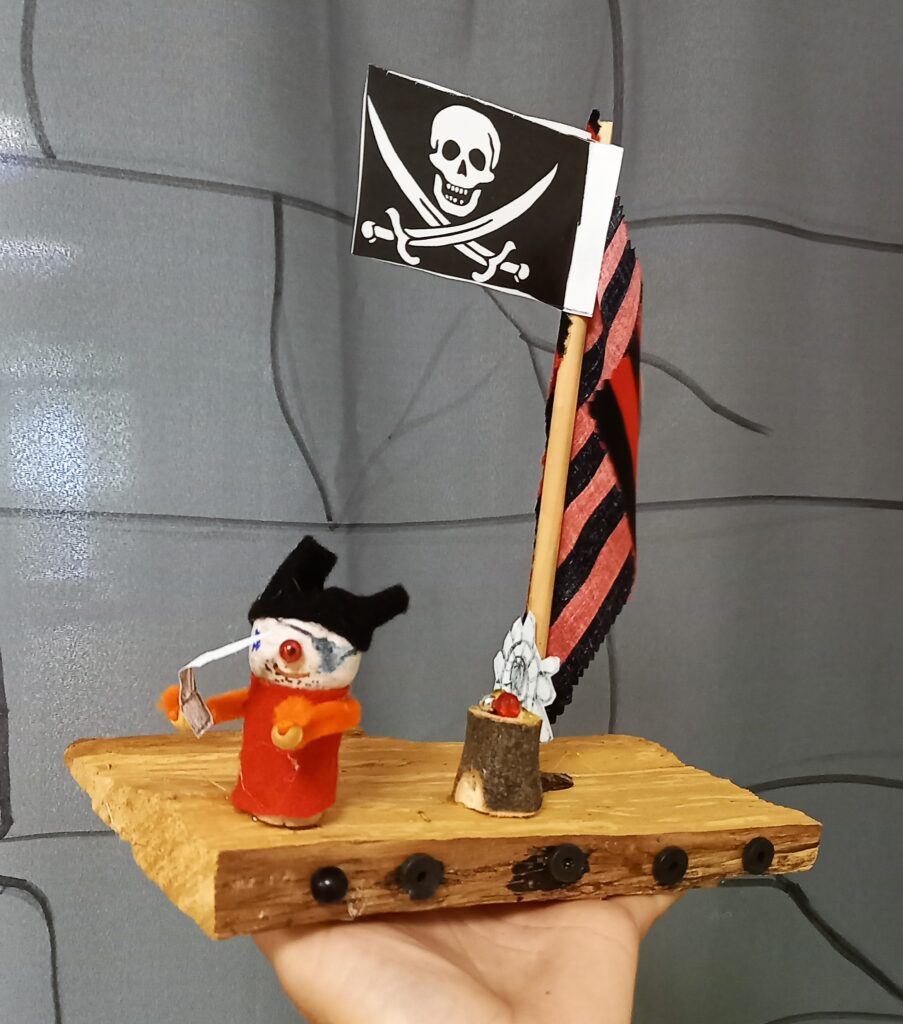 Piratenschiff mit Flagge und Kreatur auf Holzplatte.