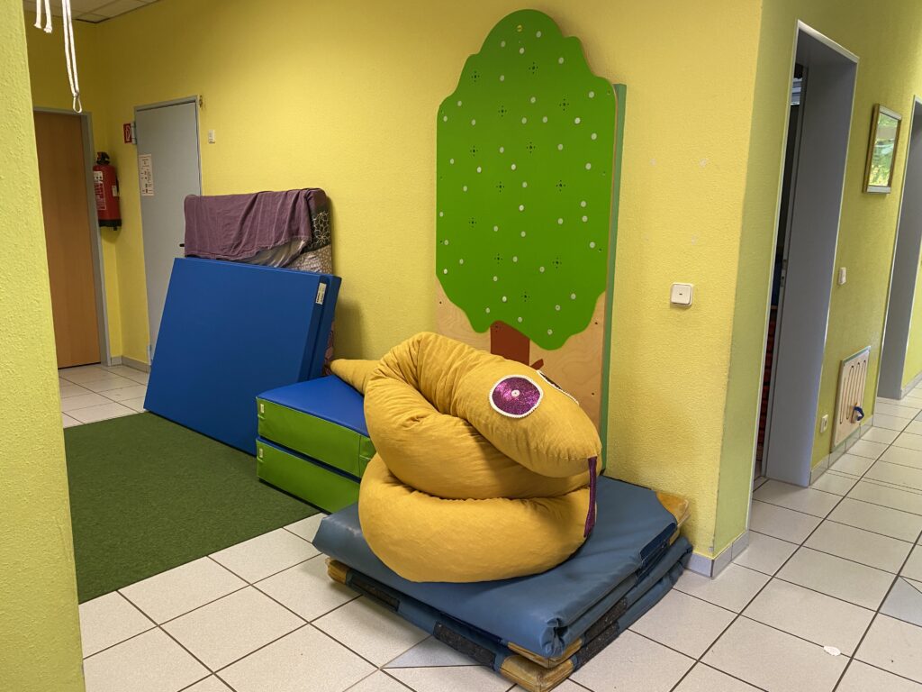Bild mit gelbem Kissen, blauen und grünen Matten sowie einer Kinderkraftmatte und einem Baummodul.