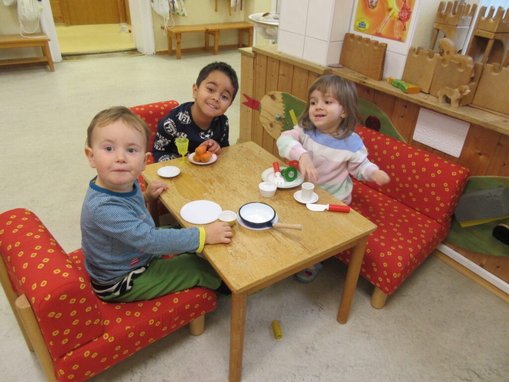 Drei Kinder beim Spiel mit Play-Doh und Kaffeetabletten in einem Kindergarten.
