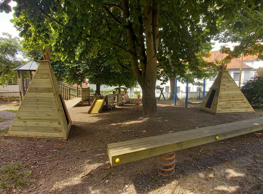 Parkplatz mit Spielanlagen und Täppchen.