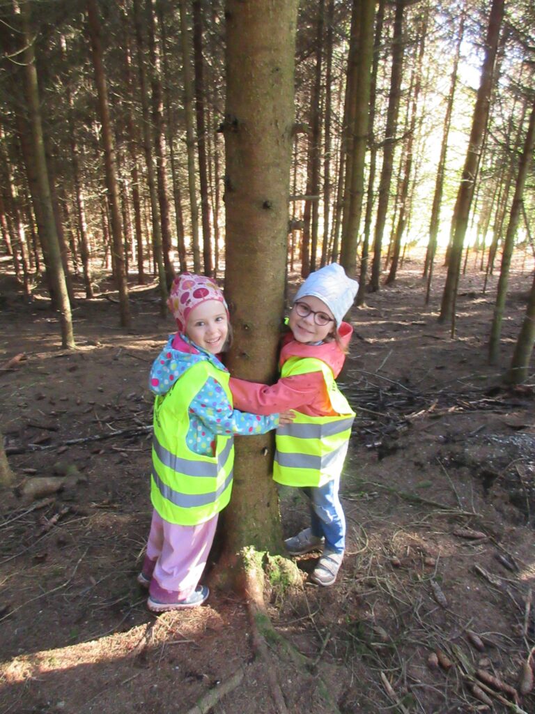 Zwei Kinder in Sicherheitswesten in einem Wald.