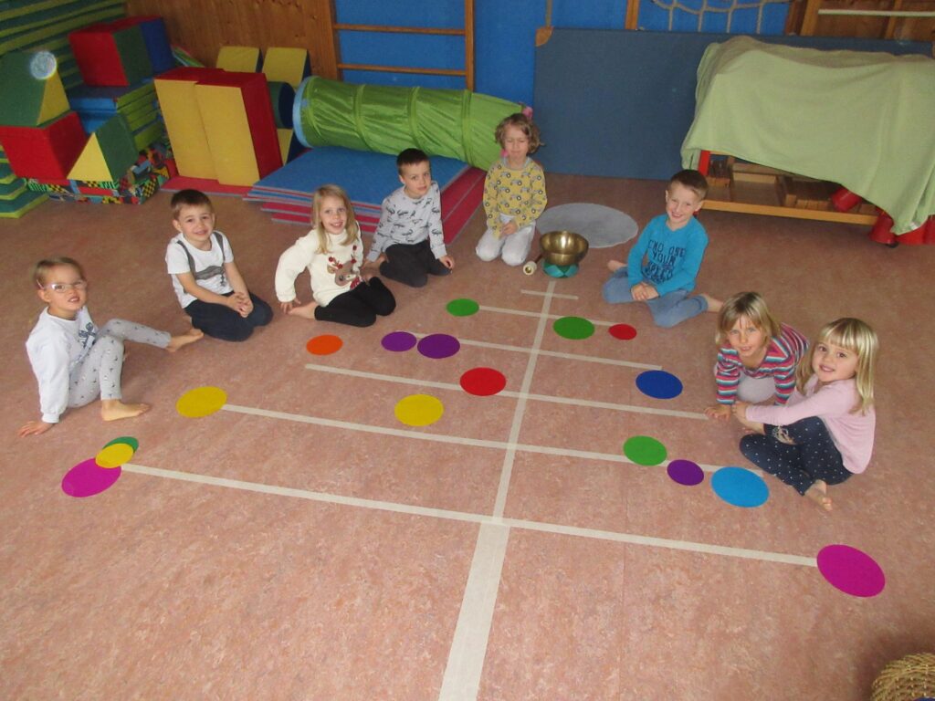 Ein Bild von Kindern in einer Spielhalle mit einem Tisch, auf dem die Kinder sitzen.